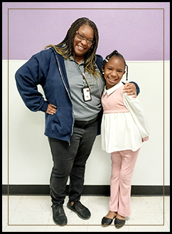 Teacher and student smiling for the camera in the school hallway